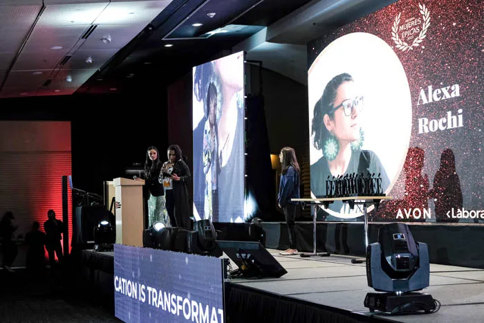Escenario de la premiación Mujeres Épicas 2022 con una pantalla que muestra el nombre «Alexa Rochi»