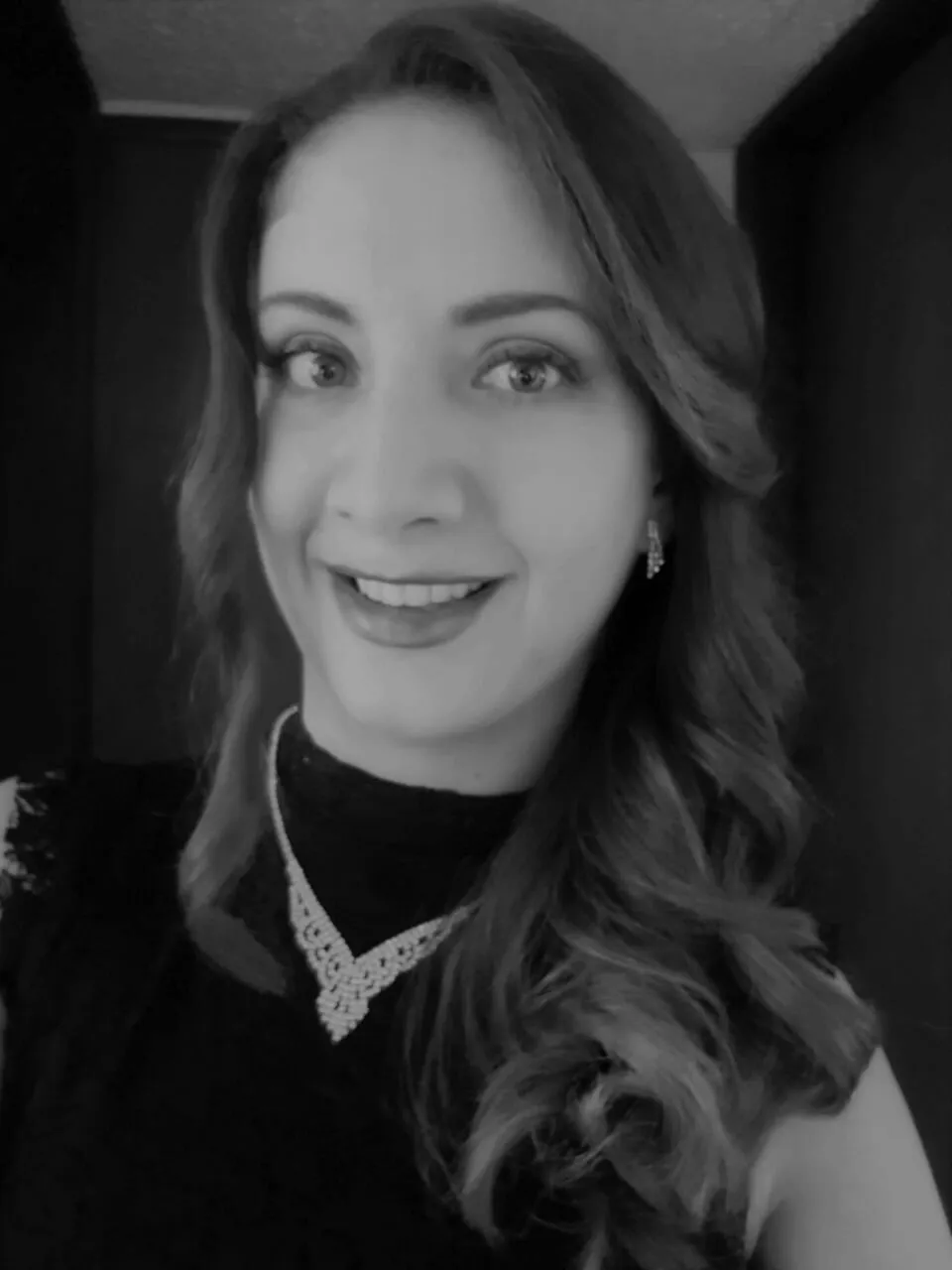 Retrato en blanco y negro de Amal Hosni Viteri, sonriente, con collar y cabello ondulado