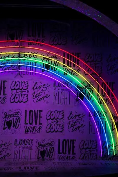 Arcoíris de neón sobre un muro cubierto de mensajes «Love» en la oscuridad