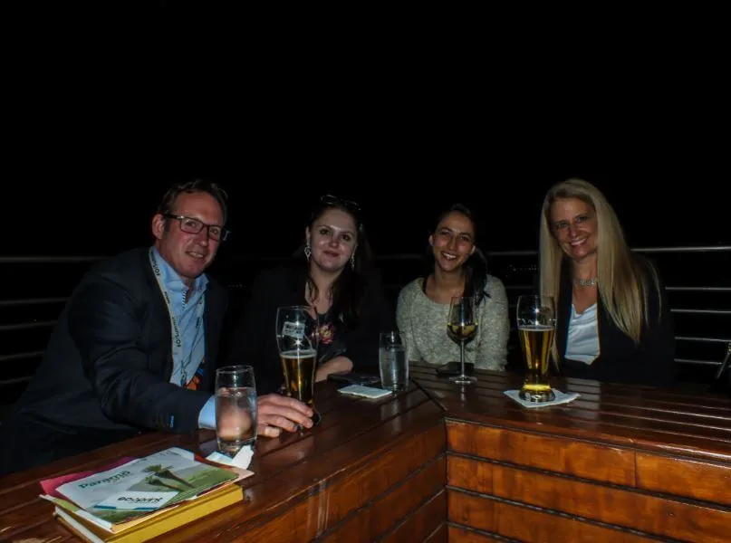 Cuatro asistentes conversan con cervezas y vino en una mesa durante el networking del foro