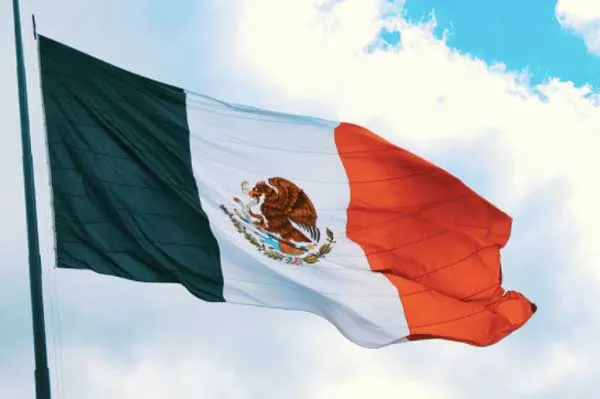 Bandera de México ondeando bajo un cielo con nubes