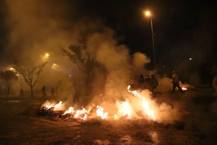 Barricada en llamas y humo en una avenida de noche durante las protestas en Colombia