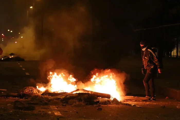 Persona de pie junto a una barricada en llamas en una calle de noche durante las protestas en Colombia