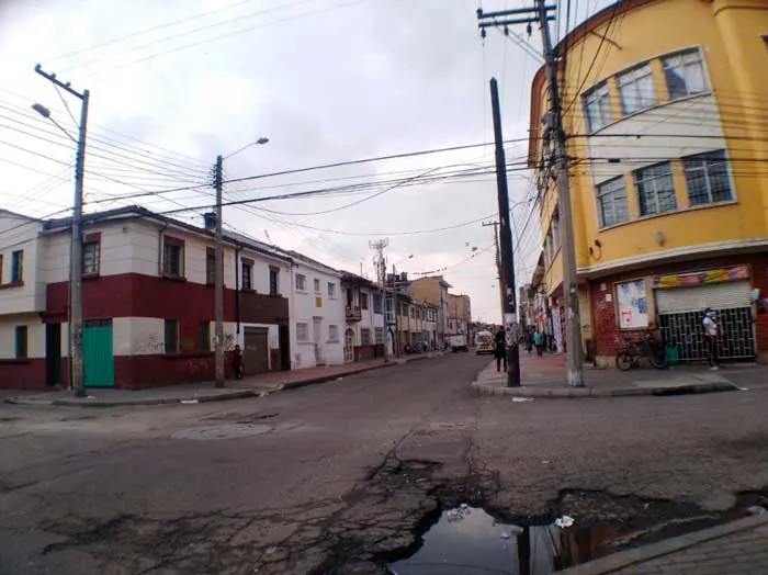Calle con un charco y casas de colores en un barrio de Bogotá, vacía durante la cuarentena