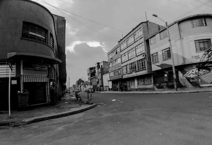 Calle amplia y desierta del barrio Santa Fe en Bogotá con edificios de varios pisos, en blanco y negro