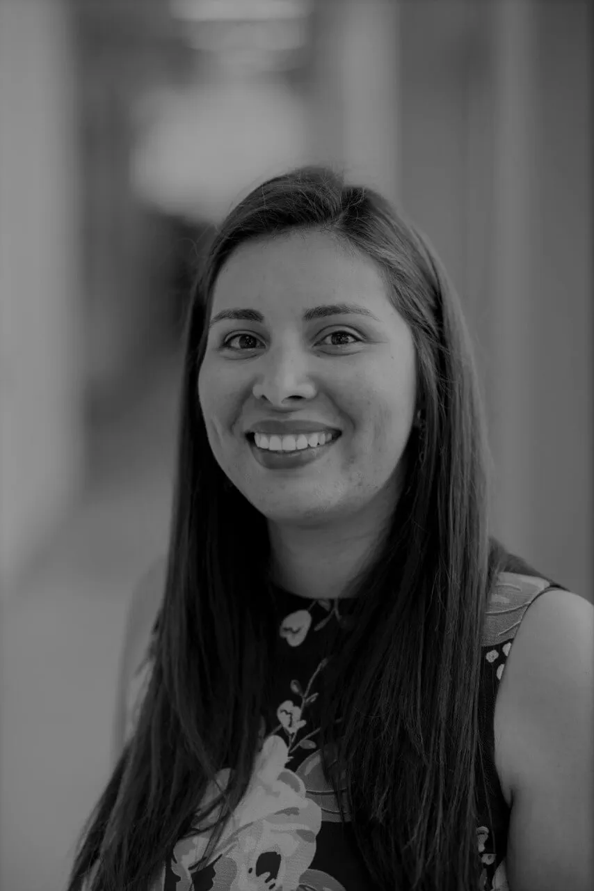 Retrato en blanco y negro de Carolina Amador Carrascal, sonriente y de cabello largo