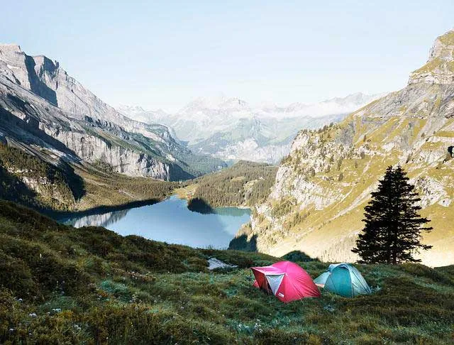 Dos carpas de camping junto a un lago rodeado de montañas