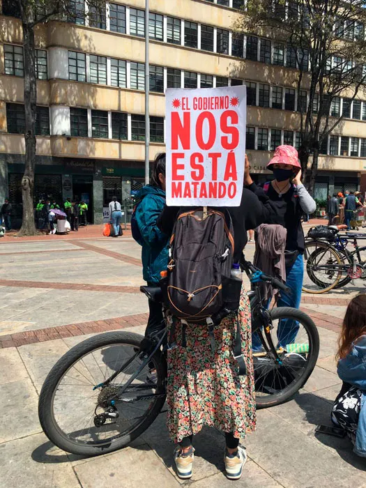 Ciclista con un cartel «El gobierno nos está matando» en una plaza durante el Paro Nacional