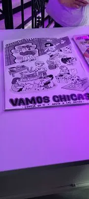 Impreso de cómic con la frase «Vamos chicas» sobre una mesa en la exposición Aletea