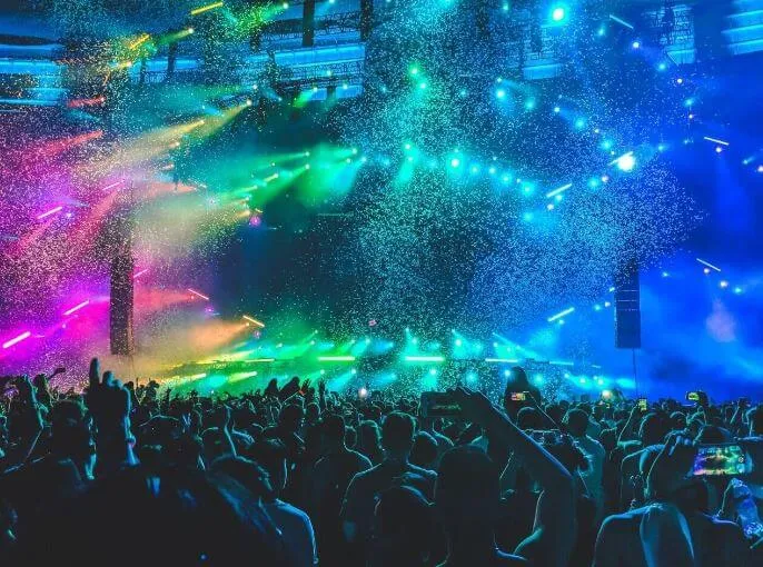 Concierto multitudinario con luces de colores y confeti sobre el público