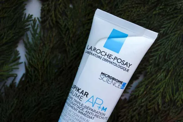 Tubo de crema hidratante La Roche-Posay sobre ramas de pino