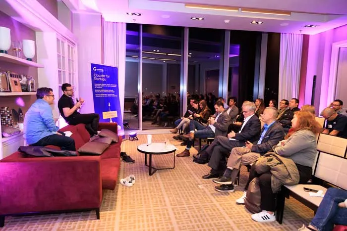 Dos hombres conversan en un sofá ante el público sentado en un evento de Clouxter