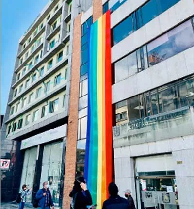 Edificio con una larga bandera arcoíris colgada en la fachada
