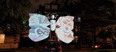 Escultura luminosa en forma de mariposa blanca en un parque de noche, parte de la exposición Aletea