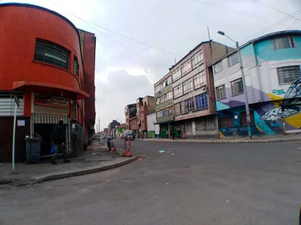 Esquina de un barrio de Bogotá con edificio rojo y mural de colores, sin tránsito de personas