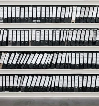Estantes blancos llenos de carpetas negras de archivo alineadas
