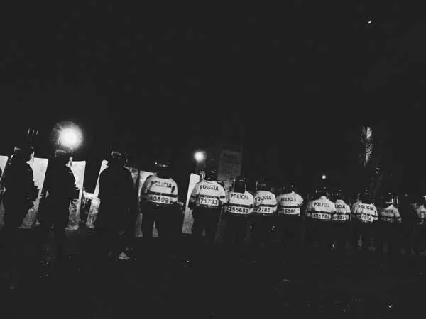 Fila de policías con chalecos reflectantes de noche en blanco y negro durante una protesta
