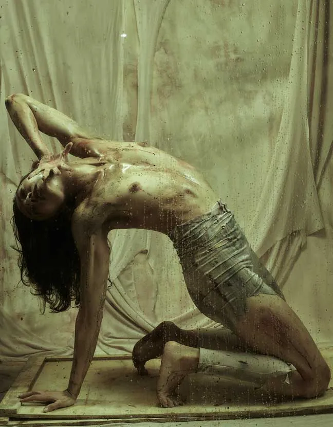Bailarina arqueada hacia atrás, arrodillada con las manos sobre la cabeza, en una foto-performance de danza contemporánea