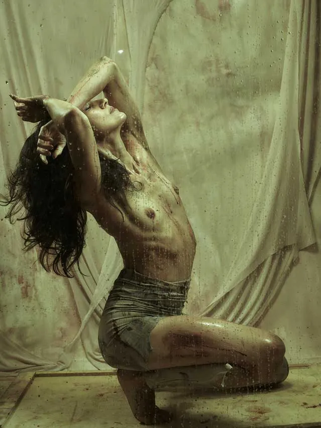 Bailarina arrodillada con los brazos sobre la cabeza y el cabello suelto, en una foto-performance de danza contemporánea