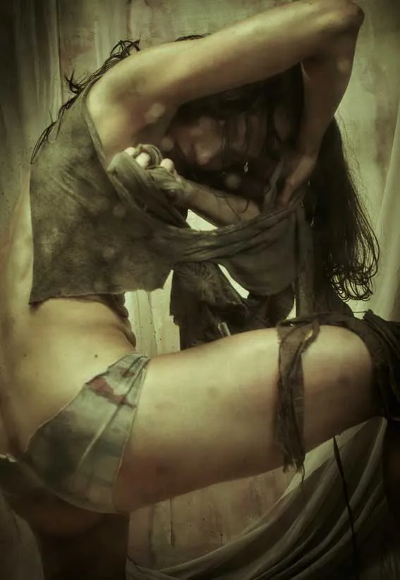 Foto-performance de una bailarina con ropa rasgada y los brazos levantados sobre la cabeza, en tonos sepia