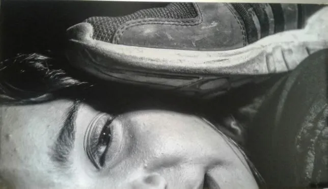 Rostro de una mujer en el suelo con una zapatilla apoyada sobre su cabeza, de la serie «¿Cómo me quedan los zapatos?»