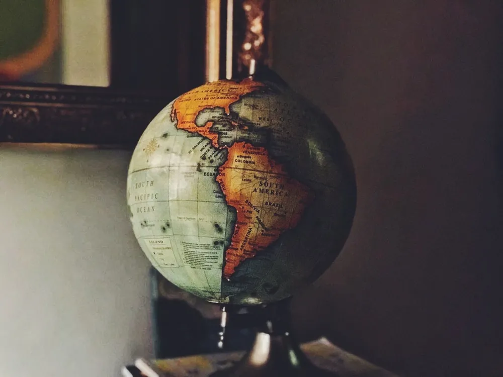 Globo terráqueo antiguo que muestra América, sobre una repisa junto a una pared oscura