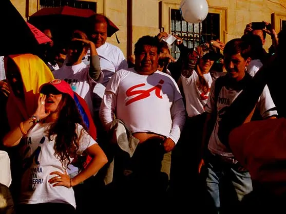 Grupo de personas con camisetas blancas, algunas con la palabra «Sí», celebra en una calle de la ciudad
