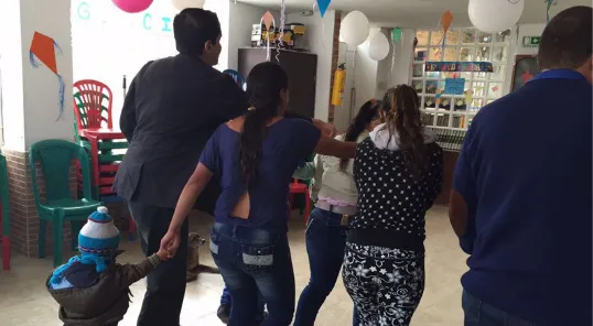 Grupo de personas conversa de pie en un salón decorado con globos durante una sesión de coaching