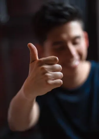 Hombre sonriente haciendo un gesto de aprobación con el pulgar hacia arriba