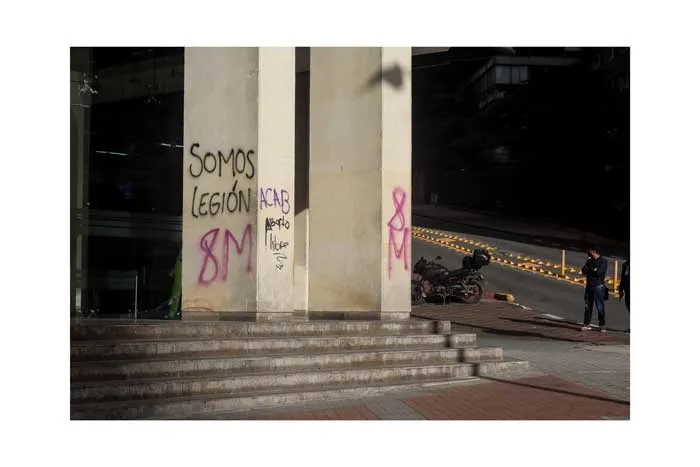Columnas de un edificio con las pintadas «Somos legión» y «8M» en rosado