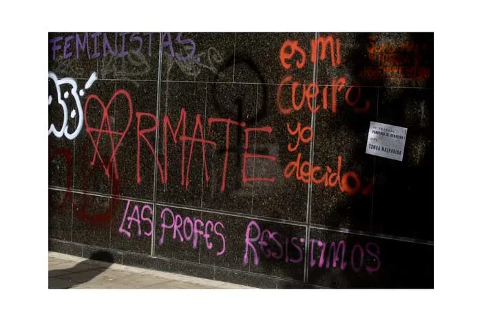 Muro negro con pintadas rojas y moradas: «Es mi cuerpo, yo decido» y «Las profes resistimos»