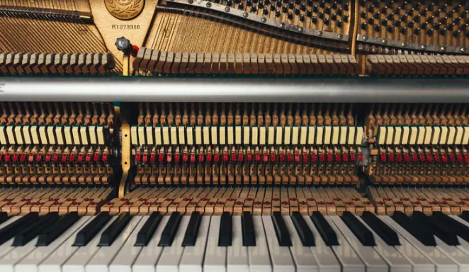 Interior de un piano con martillos y cuerdas visibles sobre el teclado