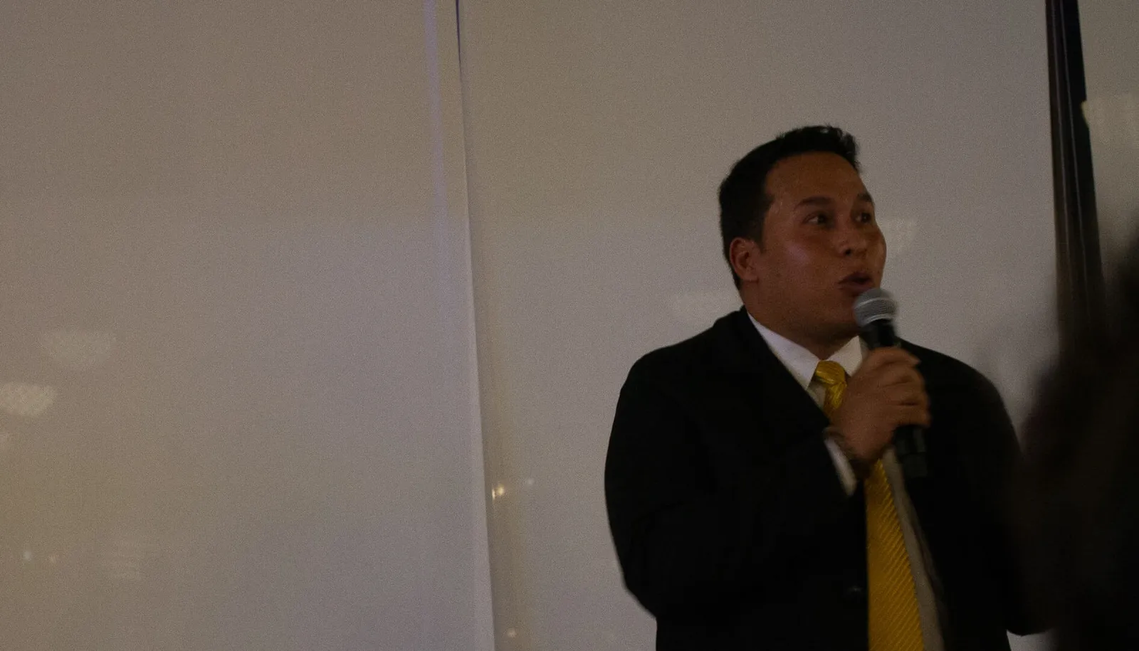 Jan del Castillo, con traje y micrófono, relata la historia de Lysmer Angeline en el lanzamiento de Revista Level