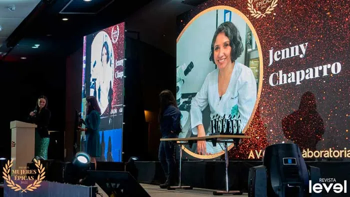 Pantalla con Jenny Chaparro y mesa de premios en el escenario de Mujeres Épicas de Revista Level