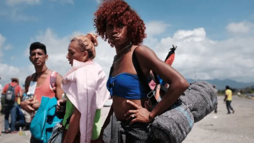 Jóvenes con mochilas y bultos de viaje en un camino, en alusión a la migración centroamericana
