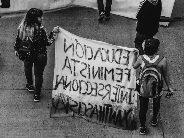 Dos jóvenes sostienen una pancarta «Educación feminista interseccional antifascista» durante la marcha