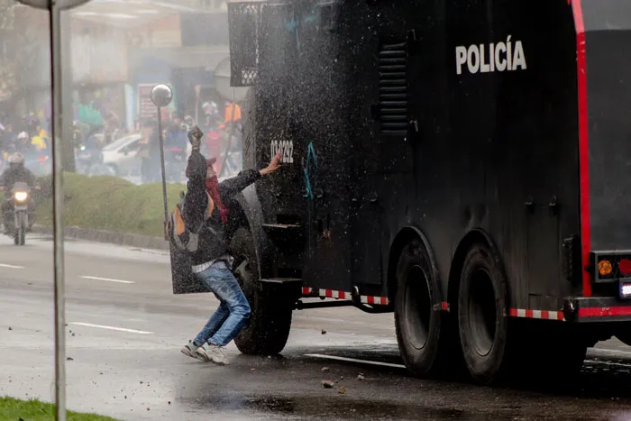 Manifestante junto a un vehículo antidisturbios de la Policía en una avenida