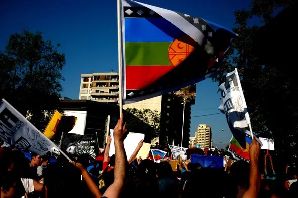 Manifestantes con banderas mapuche y pancartas en una calle de la ciudad
