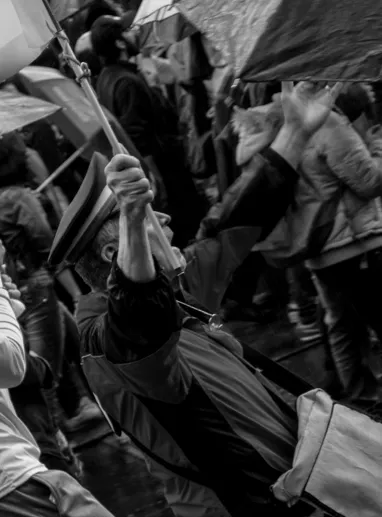 Manifestantes con banderas y puños en alto entre la multitud, en blanco y negro