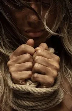 Manos de una mujer atadas con una cuerda, con el cabello cubriéndole el rostro