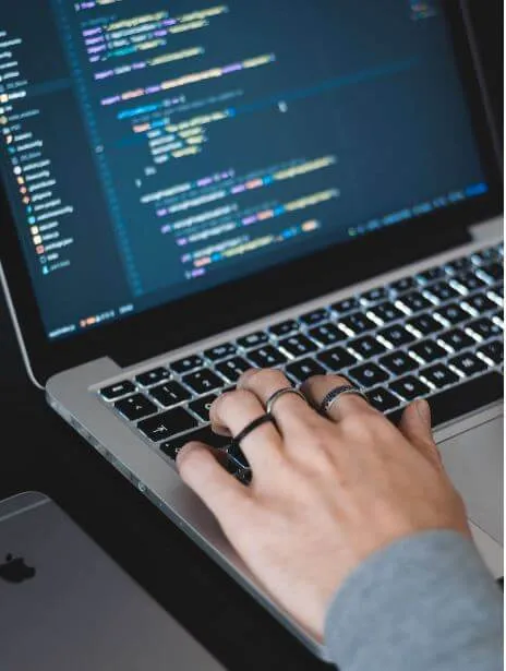 Manos escribiendo en un portátil que muestra líneas de código en pantalla