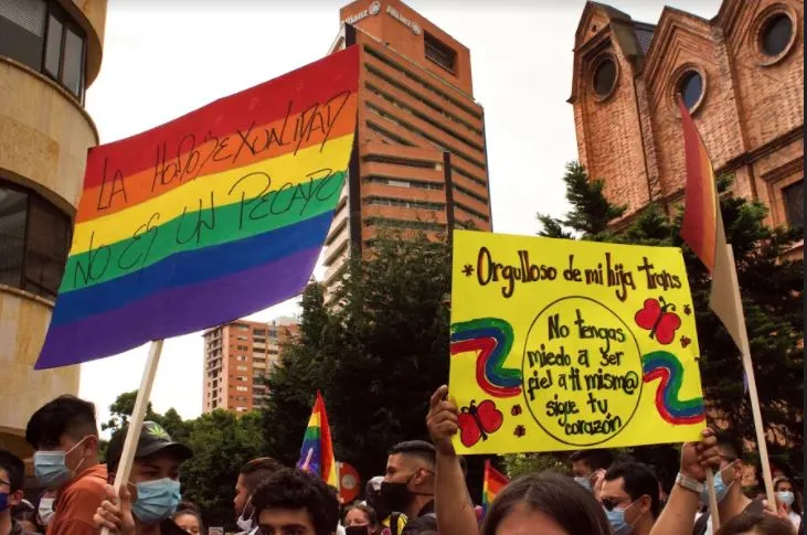 Bandera arcoíris y un cartel amarillo «Orgullo de mi hija, tienes» levantados entre la multitud de la marcha