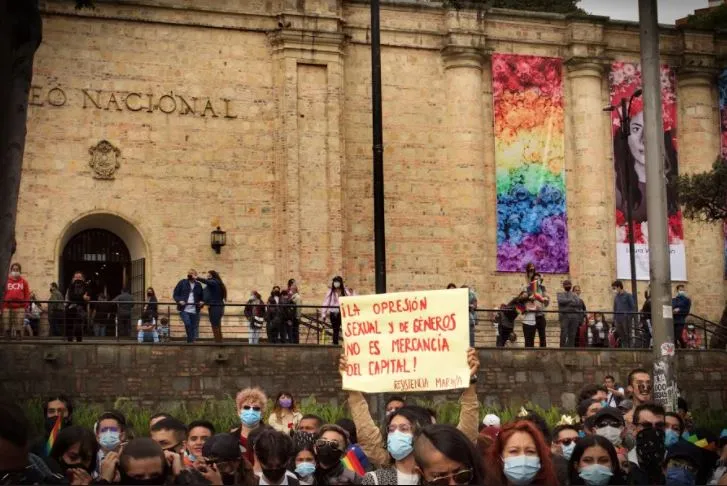 Manifestantes con un cartel amarillo frente a la fachada del Museo Nacional decorada con telas de colores