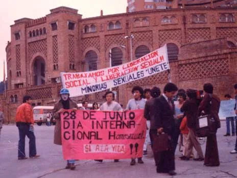 Manifestantes con pancartas «28 de junio, Día Internacional del Orgullo Homosexual» y «Minorías sexuales, únete» ante una plaza de toros, 1982