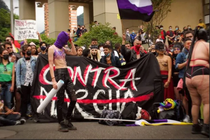 Pancarta negra con la palabra «Contra» y la palabra «marcha» tachada, sostenida por manifestantes en el Orgullo alternativo