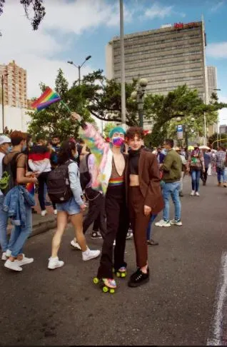 Pareja con patines camina por una avenida entre la multitud de la Marcha del Orgullo