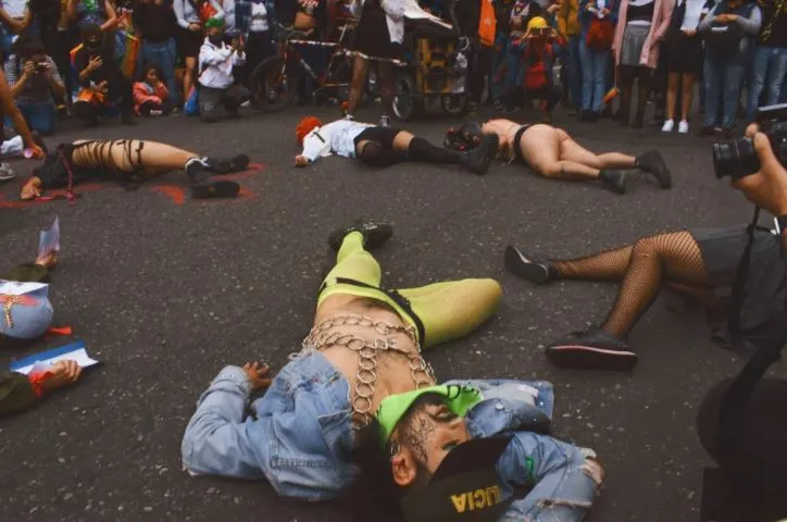 Varias personas tendidas en el asfalto en una performance frente a un círculo de espectadores