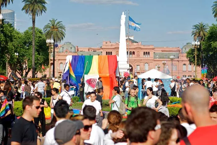 Multitud reunida en la Plaza de Mayo con una bandera del arcoíris frente a la Casa Rosada, durante una marcha del Orgullo en Argentina