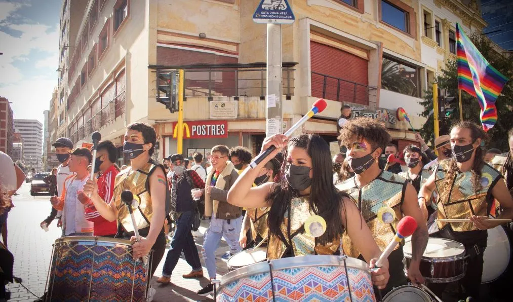 Tamborileros con petos dorados y mascarillas tocan en la calle durante la Marcha del Orgullo