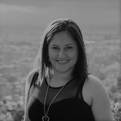 Retrato en blanco y negro de María Angélica Leal Leal, sonriente, con un paisaje de fondo